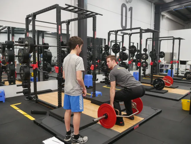 A young athlete with Sever's disease being coached on their strength exercises