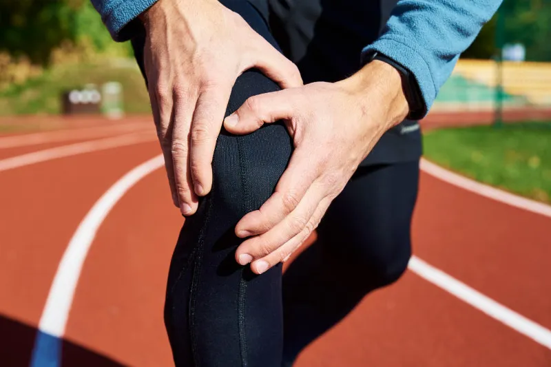 A man holds his knee with Osgood pain